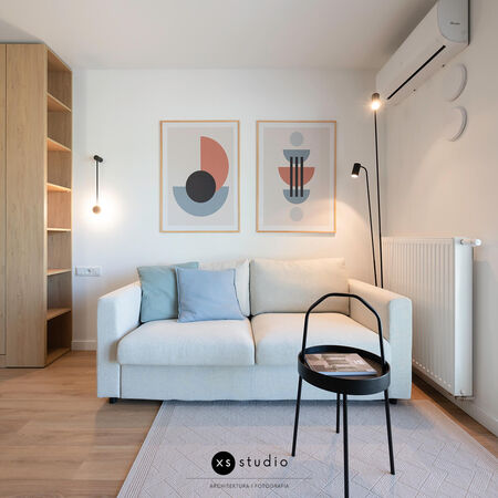 Wnętrze salonu w stylu skandynawskim z jasną sofą i drewnianymi detalami.