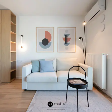 Wnętrze salonu w stylu skandynawskim z jasną sofą i drewnianymi detalami.
