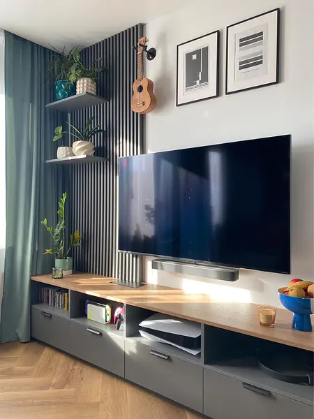 Salon z telewizorem, roślinami i minimalistycznym wystrojem.