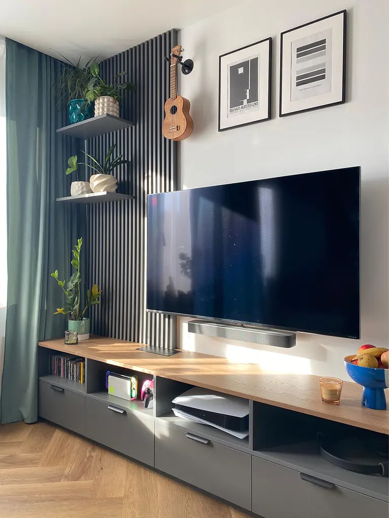 Salon z telewizorem, roślinami i minimalistycznym wystrojem.