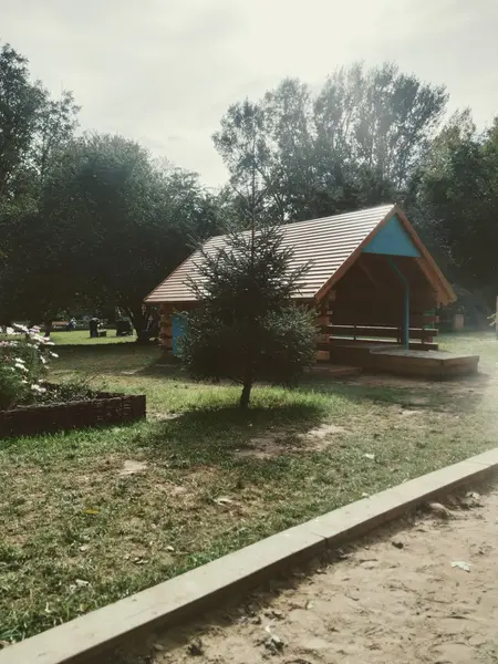 Domek ogrodowy z drewnianym tarasem otoczony zielenią, tradycyjny styl.