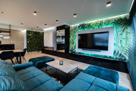 Nowoczesny salon z zielonymi roślinami, telewizorem i elegancką sofą.