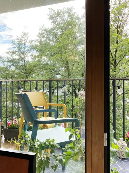 Balkon z kolorowymi krzesłami, roślinami i widokiem na zieleń, minimalistyczny, nowoczesny.