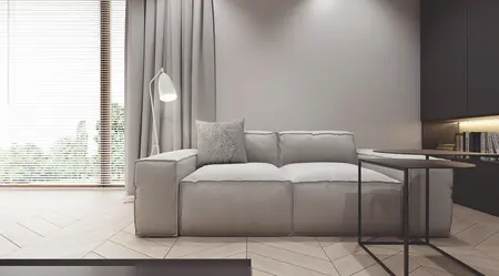 Wnętrze salonu z szarym narożnikiem, lampą i drewnianą podłogą w nowoczesnym stylu.