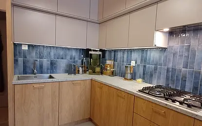 Kuchnia w stylu eklektycznym, nowoczesnym z soft minimalizmem, z drewnianymi meblami i niebieskimi płytkami.