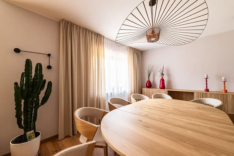 Wnętrze jadalni z okrągłym stołem, drewnianymi krzesłami i roślinami. Styl boho, industrialny i skandynawski.