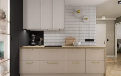Nowoczesna kuchnia z jasnymi, matowymi szafkami, drewnianym blatem i minimalistycznymi złotymi uchwytami. Ściana wykończona białymi, pionowymi płytkami oraz dwie designerskie lampy ścienne nadają wnętrzu elegancji.