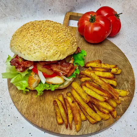 Pyszny burger z bekonem, sałatą, pomidorem i frytkami na desce