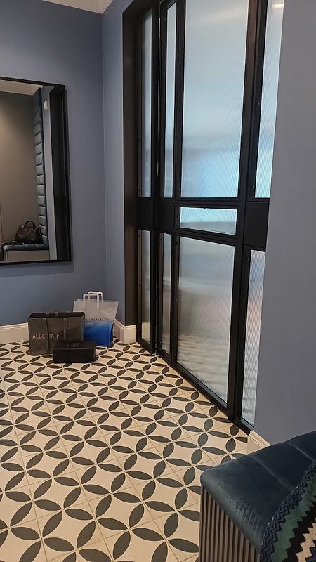 Przedpokój z niebieskimi ścianami, lustrzanym odbiciem i elegancką podłogą w stylu glamour.