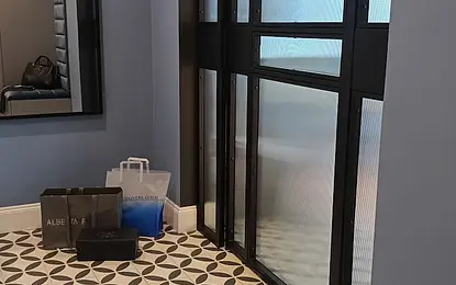 Przedpokój z niebieskimi ścianami, lustrzanym odbiciem i elegancką podłogą w stylu glamour.