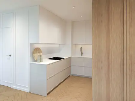 Kuchnia w stylu japandi i minimalistycznym z białymi meblami i drewnianymi detalami.