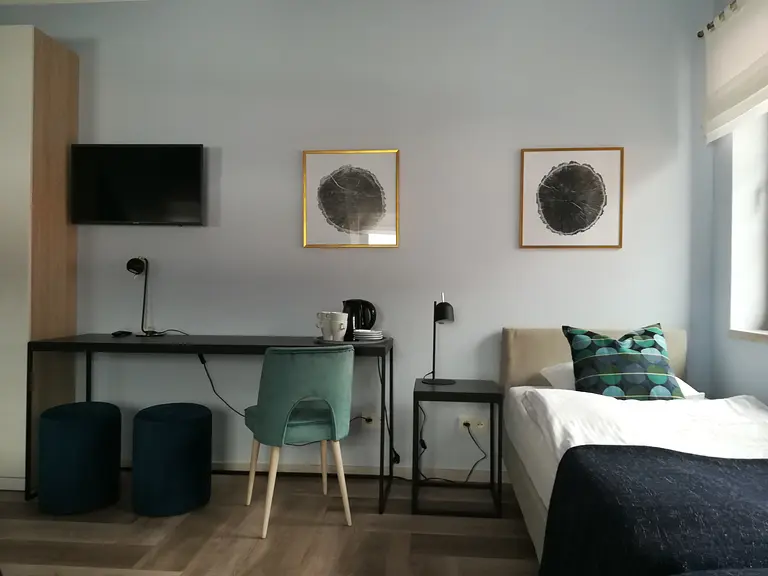 Wnętrze pokoju z biurkiem, telewizorem i łóżkiem w stylu minimalistycznym, nowoczesnym, współczesnym.