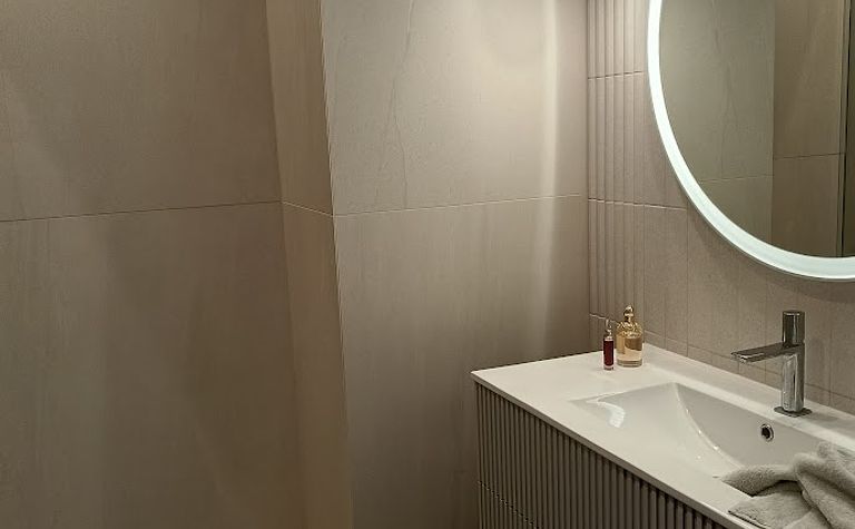 Wnętrze nowoczesnej łazienki z umywalką i dużym lustrem.