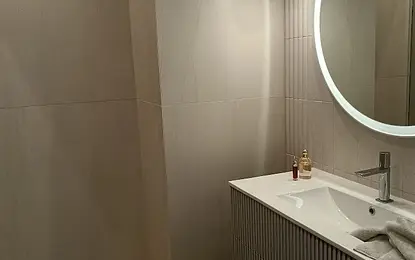 Wnętrze nowoczesnej łazienki z umywalką i dużym lustrem.