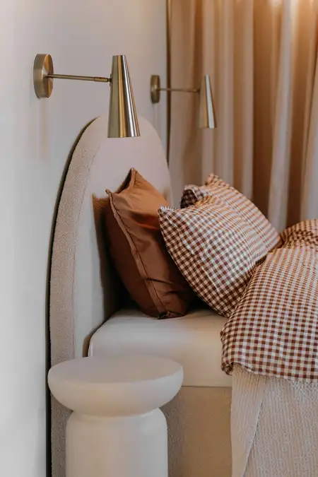 Sypialnia w stylu quiet luxury z beżowym łóżkiem i vintage poduszkami.