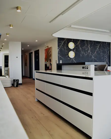 Eklektyczne wnętrze z białą komodą, czarnymi detalami i nowoczesnym oświetleniem.