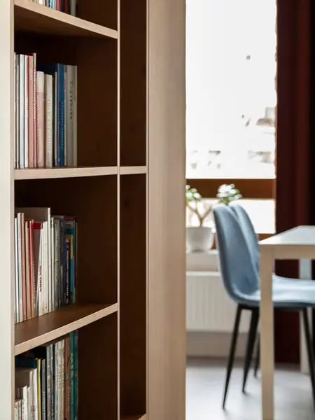 Minimalistyczne wnętrze z regałem na książki i niebieskimi krzesłami