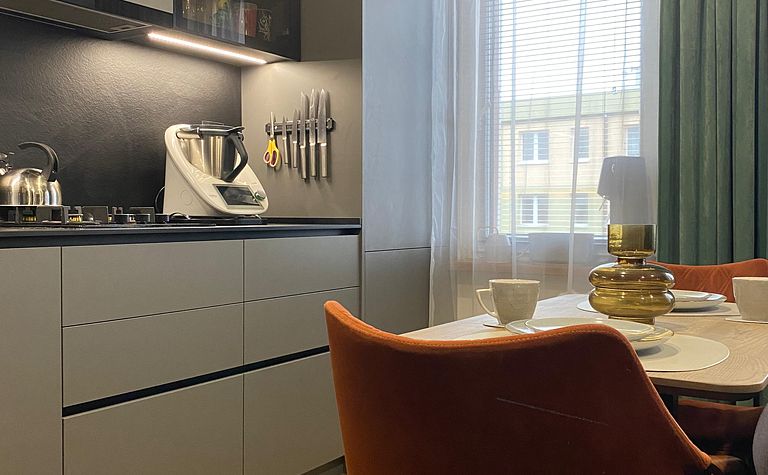 Nowoczesna kuchnia z szarymi meblami i brązowymi detalami, minimalistyczny design.