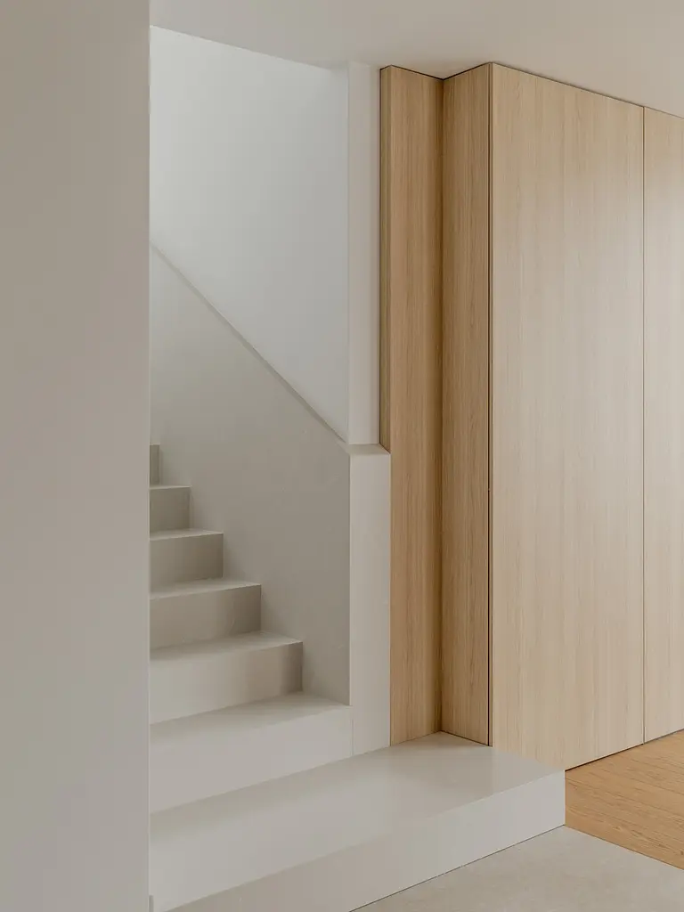 Przedpokój w stylu japandi z drewnianymi schodami i minimalistycznym wystrojem.