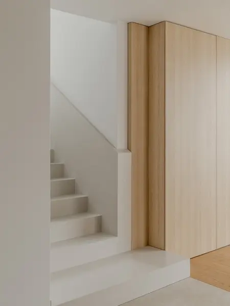 Przedpokój w stylu japandi z drewnianymi schodami i minimalistycznym wystrojem.