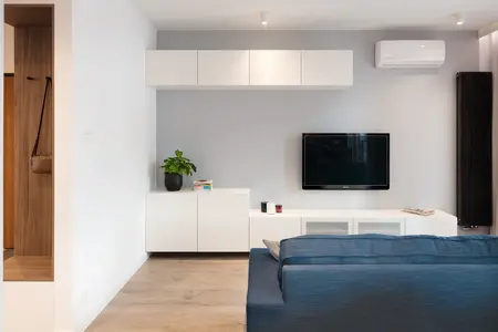 Wnętrze salonu z niebieską sofą i białymi meblami, nowoczesny design.