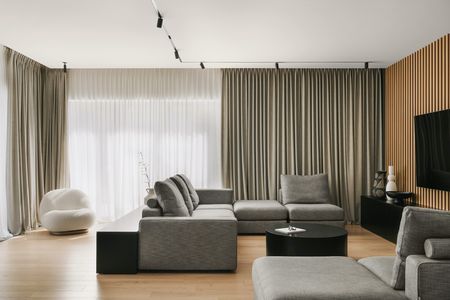 Wnętrze salonu w stylu industrialnym i minimalistycznym z szarymi meblami i drewnianymi detalami.