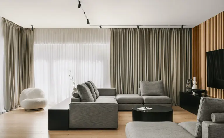 Wnętrze salonu w stylu industrialnym i minimalistycznym z szarymi meblami i drewnianymi detalami.
