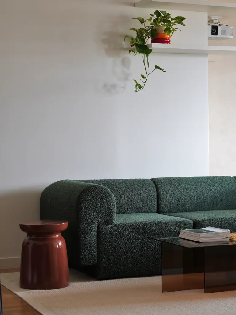 Salon z zieloną sofą, szklanym stolikiem i rośliną w doniczce, nowoczesny design.