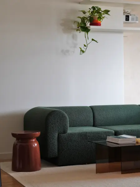 Salon z zieloną sofą, szklanym stolikiem i rośliną w doniczce, nowoczesny design.