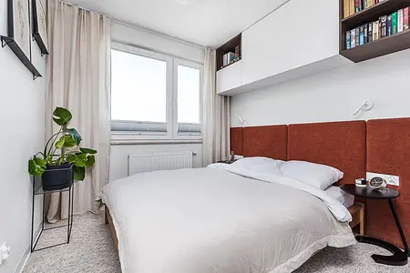 Sypialnia w stylu japandi, vintage i współczesnym z brązowym zagłówkiem i rośliną