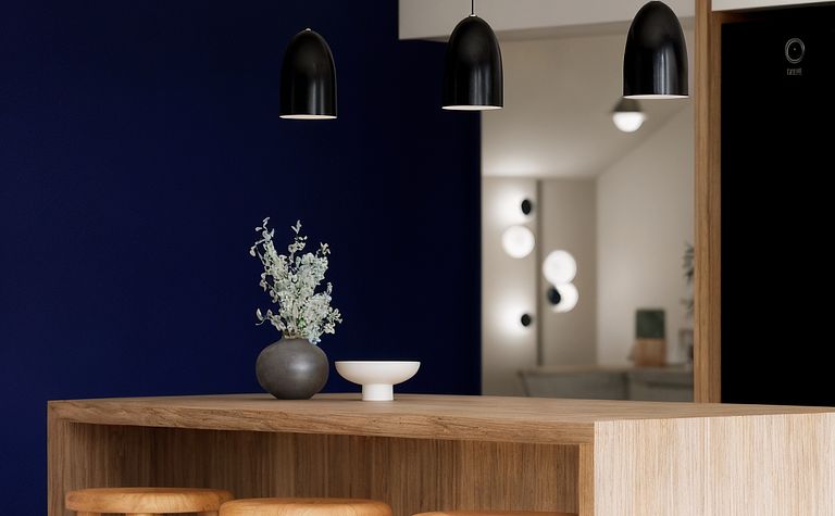 Wnętrze kuchni z drewnianym blatem, czarnymi lampami i niebieską ścianą, styl dopamine decor.
