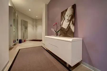 Przedpokój minimalistyczny z białą komodą i lustrami.