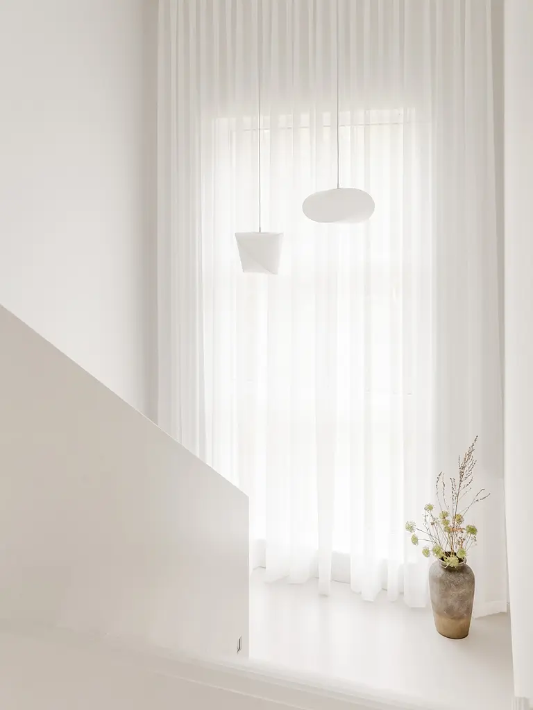 Przedpokój w stylu japandi z białymi zasłonami i minimalistycznymi lampami.