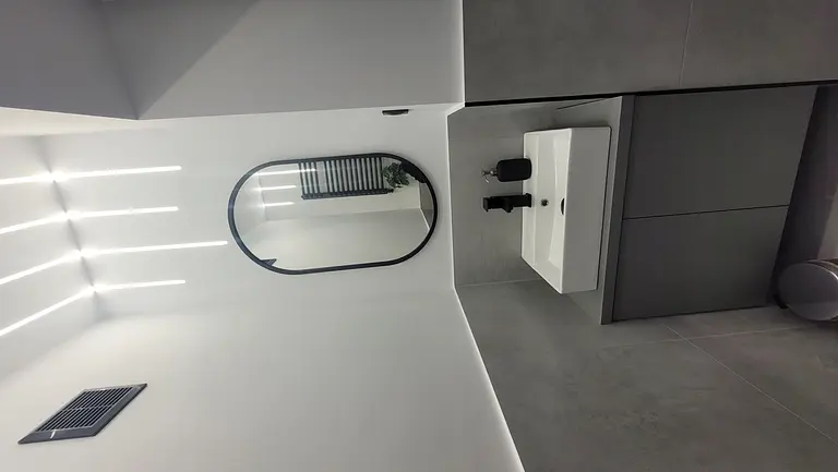 Nowoczesna łazienka z białą umywalką i szarymi płytkami w stylu minimalistycznym.