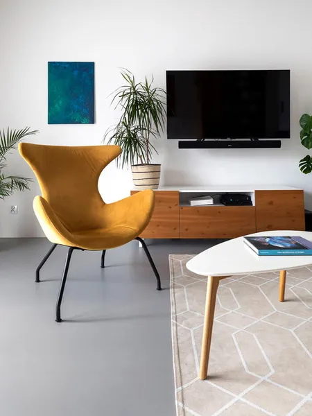 Wnętrze minimalistycznego salonu z żółtym fotelem, telewizorem i roślinami