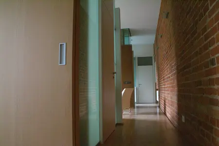 Korytarz w stylu eklektycznym z ceglaną ścianą i drewnianymi elementami.