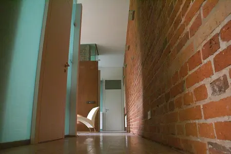 Korytarz w stylu eklektycznym i industrialnym z ceglaną ścianą i nowoczesnymi drzwiami.