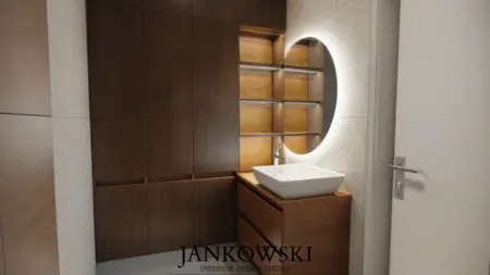 Stylowa łazienka z drewnianymi elementami, okrągłym lustrem i minimalistycznym wystrojem.