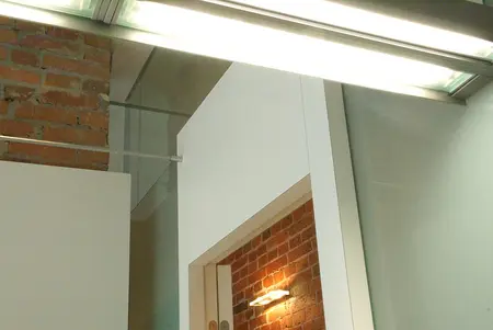 Eklektyczne wnętrze z industrialnym akcentem, biała ściana i ceglana konstrukcja.