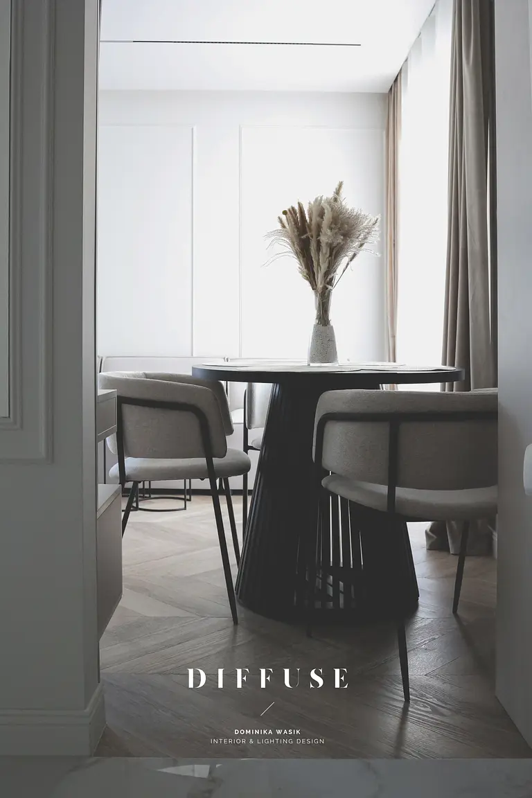 Jadalnia w stylu boho i minimalistycznym z okrągłym stołem i szarymi krzesłami.