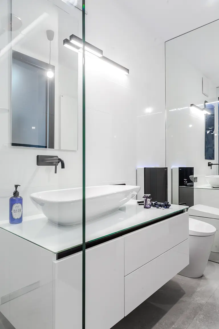 Nowoczesna łazienka z białą umywalką i czarnymi detalami, minimalistyczny design.