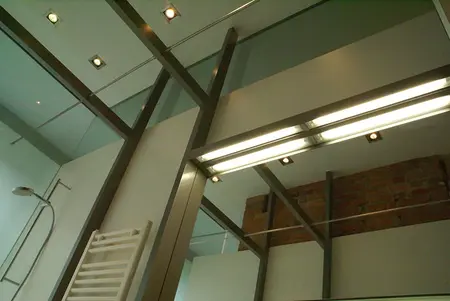 Wnętrze łazienki w stylu eklektycznym i industrialnym z szklanym prysznicem.