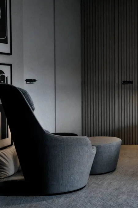 Minimalistyczny salon z szarym fotelem i nowoczesnym akcentem.