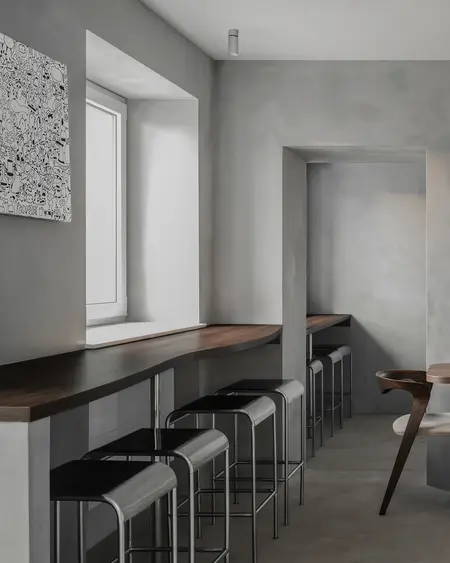 Wnętrze kuchni w stylu industrialnym z minimalistycznym drewnianym blatem i szarymi ścianami.