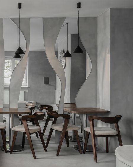 Wnętrze jadalni w stylu industrialnym i minimalistycznym z drewnianym stołem i szarymi ścianami.