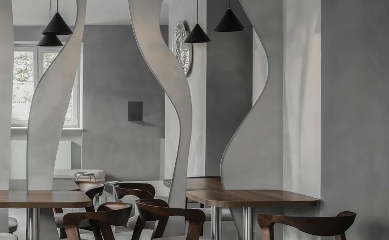 Wnętrze jadalni w stylu industrialnym i minimalistycznym z drewnianym stołem i szarymi ścianami.