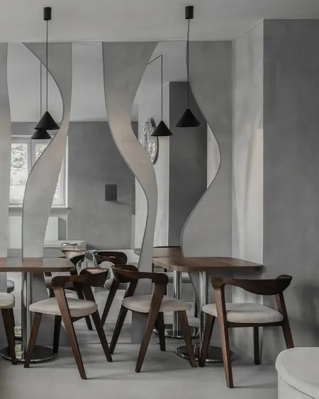 Wnętrze jadalni w stylu industrialnym i minimalistycznym z drewnianym stołem i szarymi ścianami.