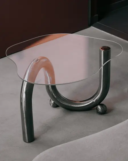Stół w stylu industrialnym, minimalistycznym z metalową podstawą i szklanym blatem.