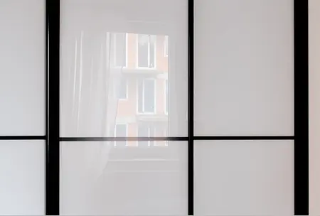 Przeszklona ściana z czarnymi detalami w minimalistycznym wnętrzu