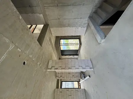 Wnętrze budynku z betonowymi ścianami i dużymi oknami, nowoczesny design.